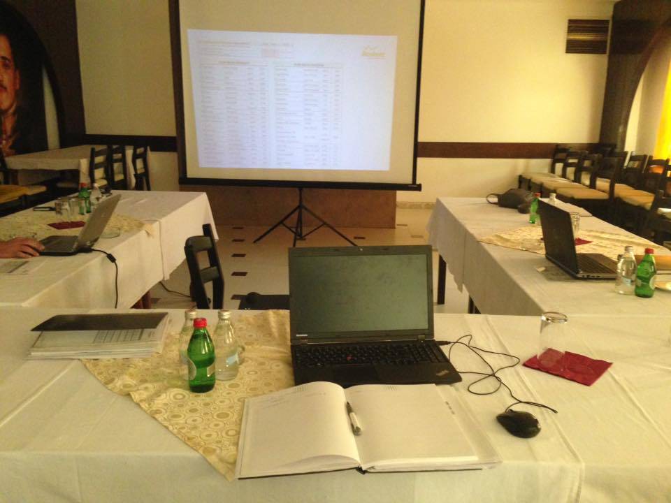 Slika stola na kome se nalazi laptop preko koga se pušta prezentacija tokom jedne konferencije