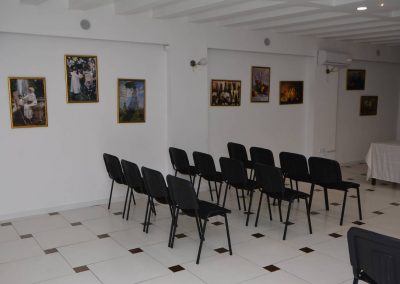 Crne stolice u kongresnoj sali sa slikama na belom zidu